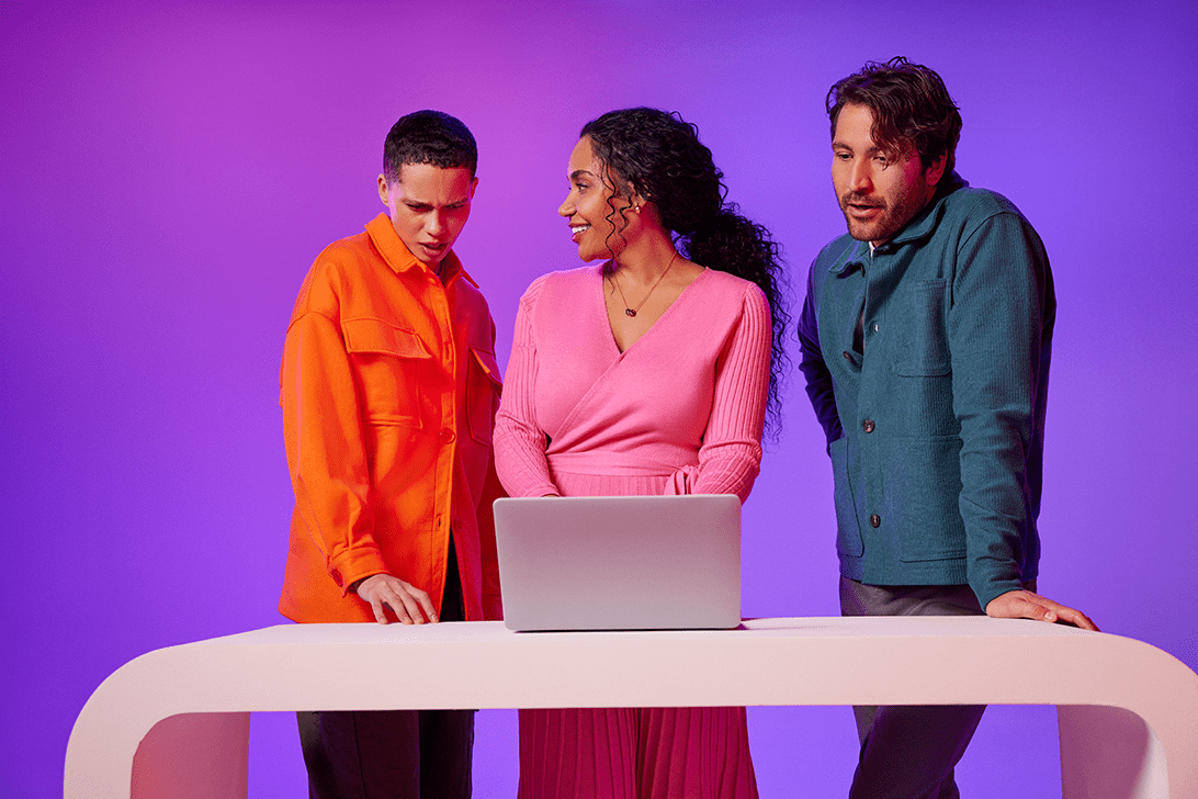 three people looking at laptop at a desk