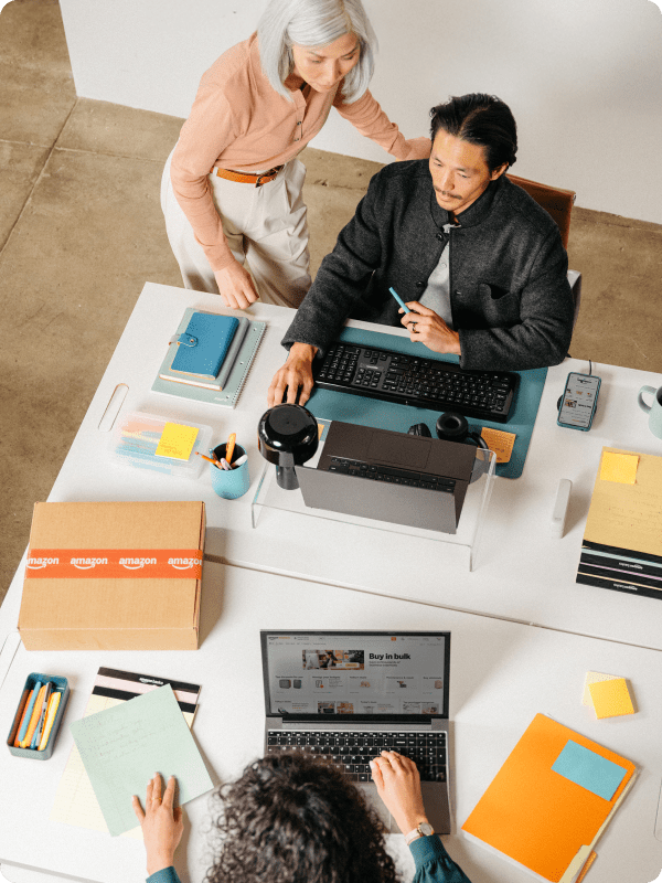 Birds eye view of three people at a desk working next to an Amazon box