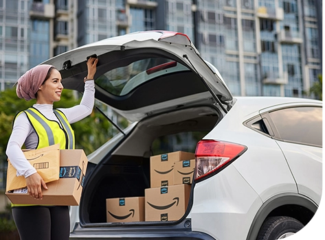 Delivery woman in safety vest with Amazon packages closing her trunk