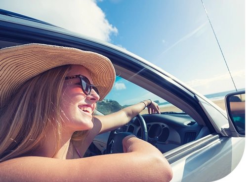 Person enjoying summer road trip, wearing sunhat and sunglasses while driving