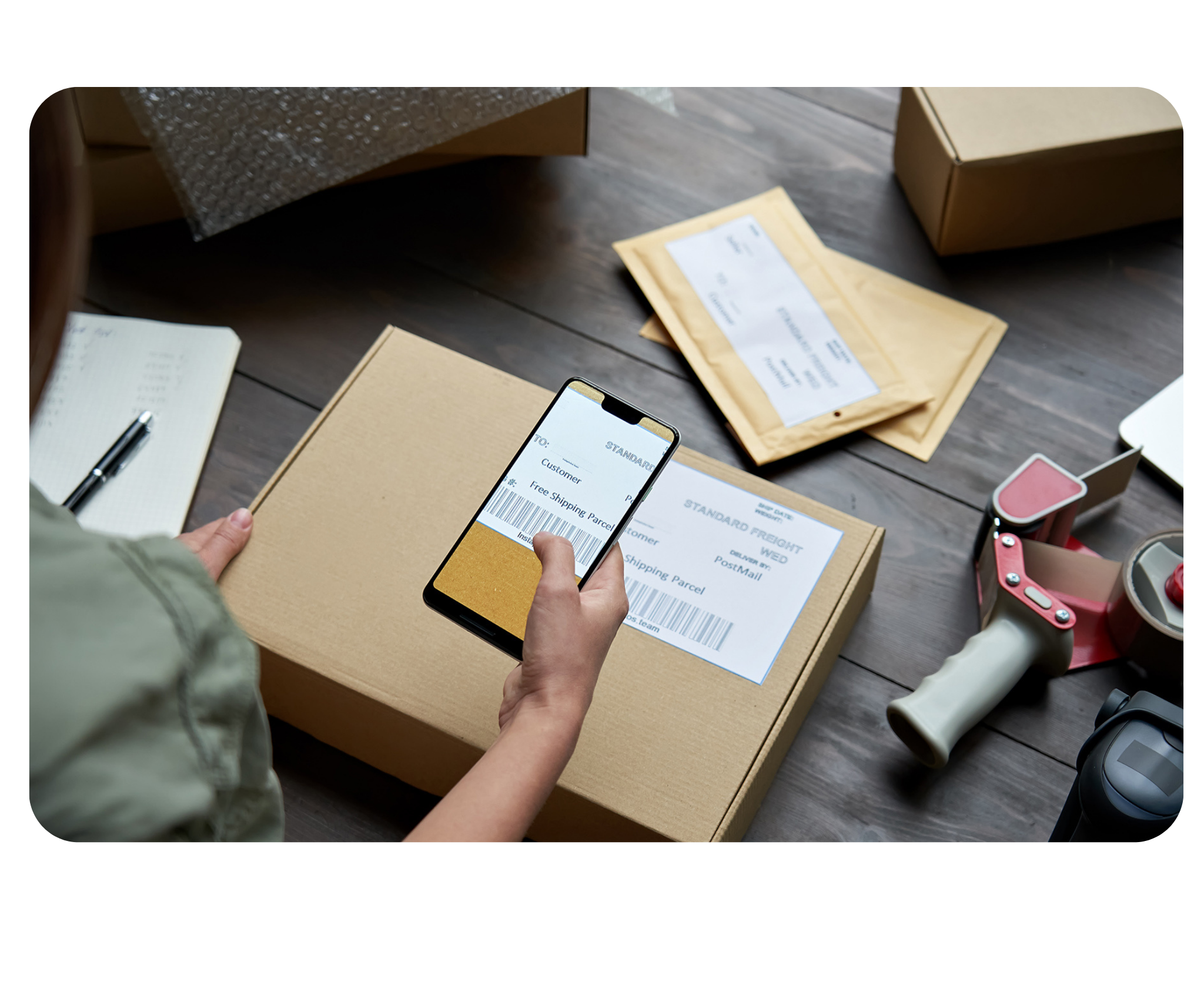 Pessoa escaneando código de barras de pacote com smartphone para rastreamento
de envio