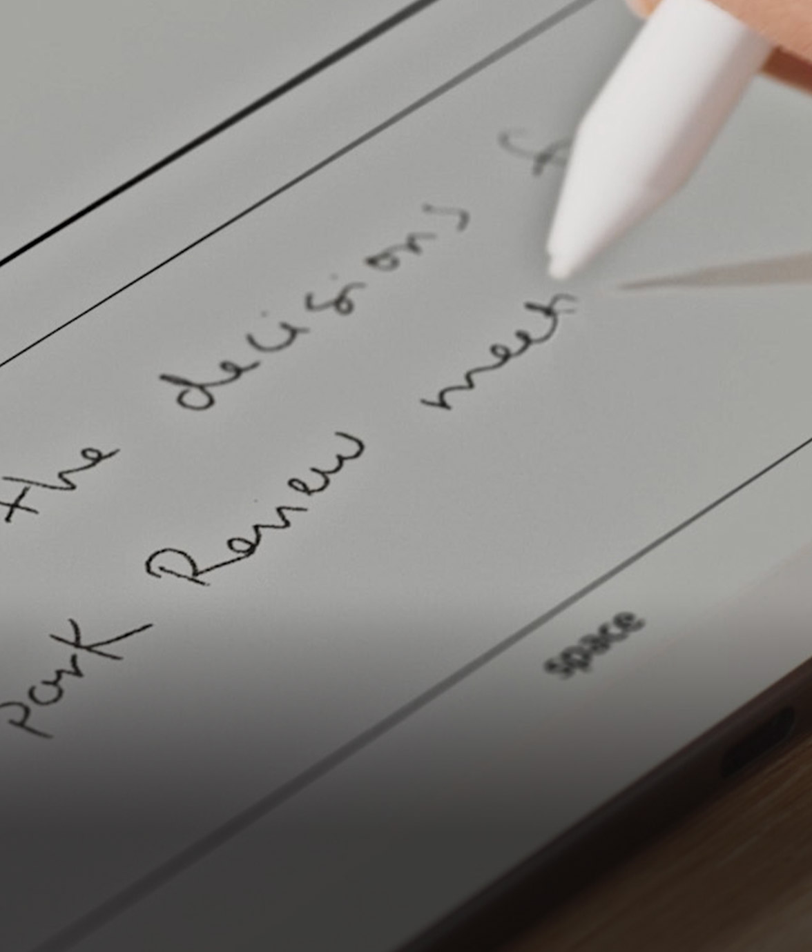 Close-up of a hand writing with Kindle Scribe without front light pen on the screen, capturing handwritten text.