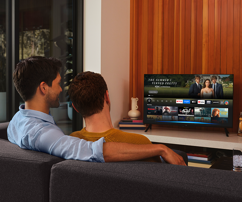 In a living room, a couple watches a movie on Fire TV from their couch. 