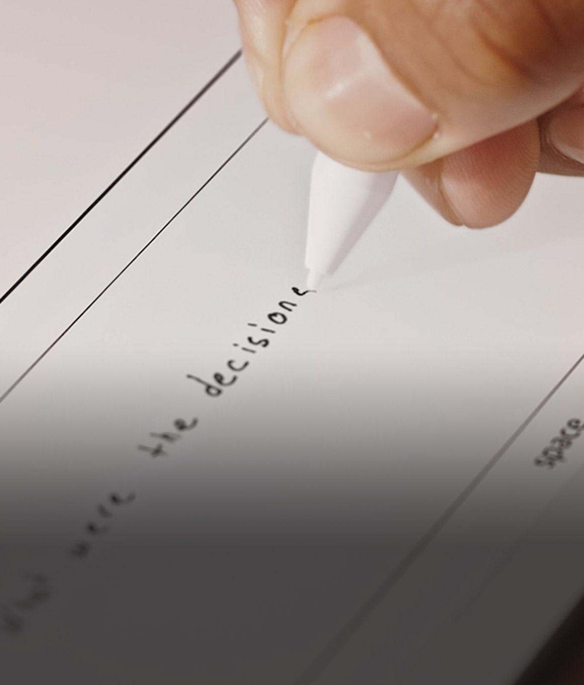 Close-up of a hand writing with the Kindle pen on Kindle Scribe, showing handwritten text forming on the screen in real time.