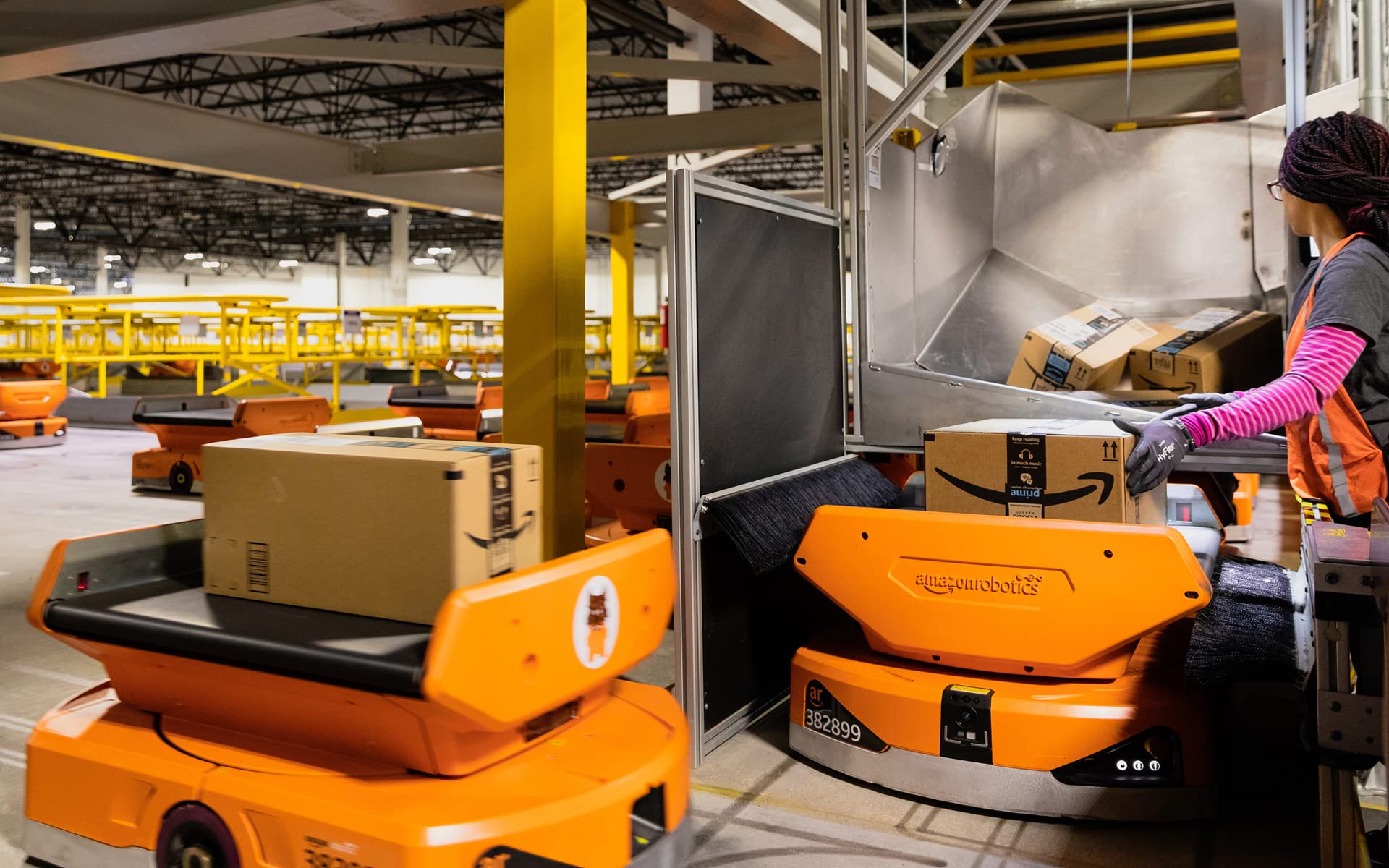 Two Amazon robots carrying packages in a warehouse