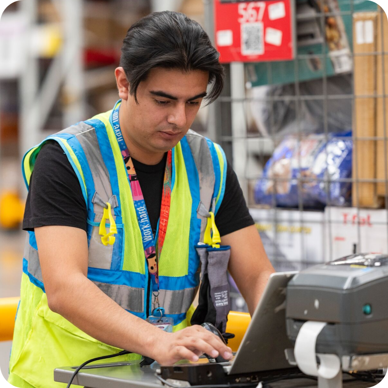 Amazon delivery station associate sorting packages using a handheld scanner