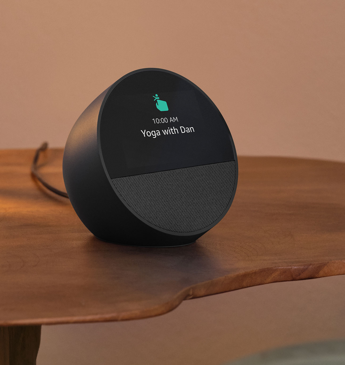 Echo Spot is on a bedside table. The 2.8-inch display shows the reminder "10:00 AM Yoga with Dan" and a pointing finger reminder icon.