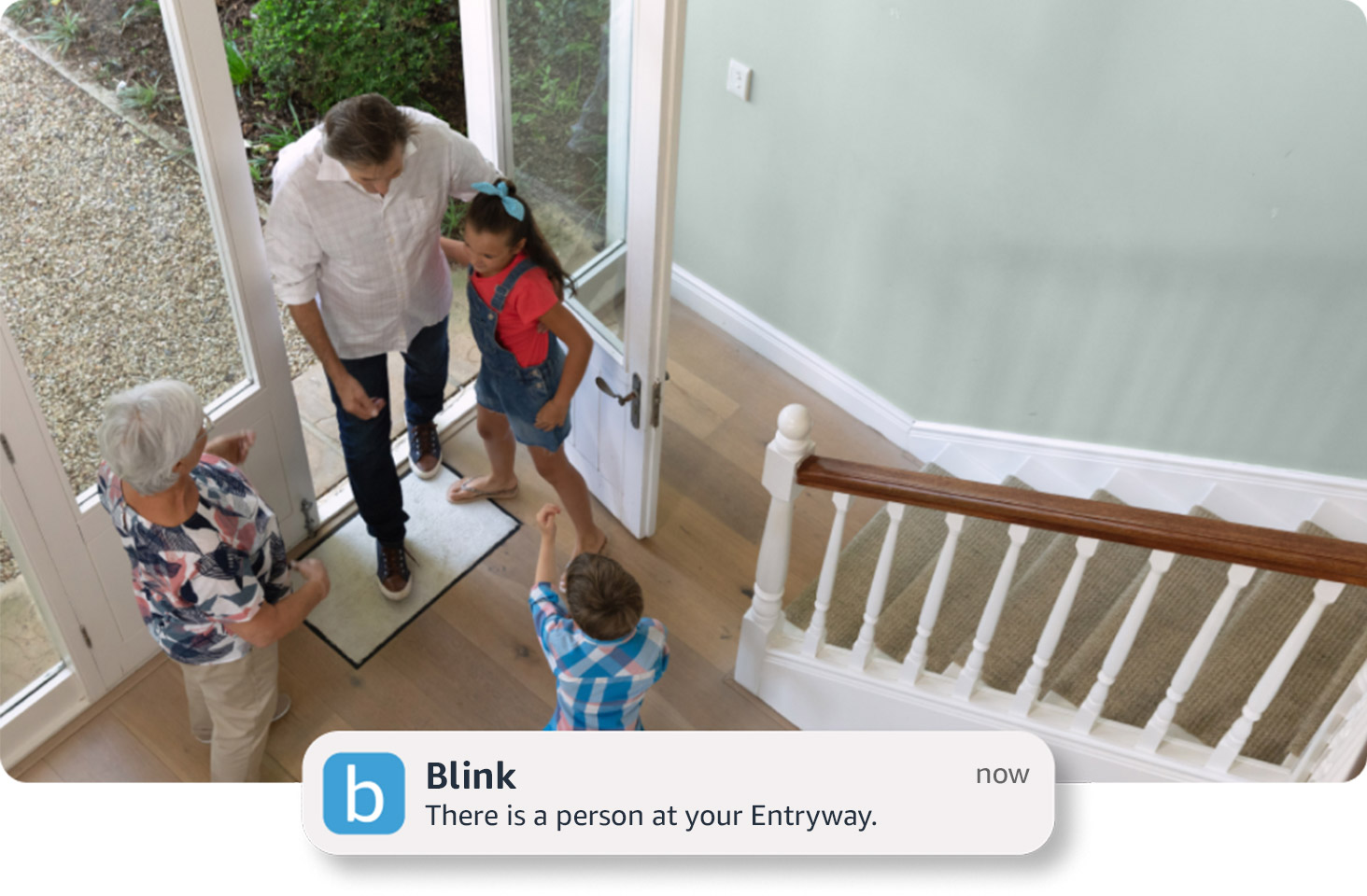 A live view image of a family's entryway with children greeting somebody at the door. On the bottom, a notification from the Blink app "There is a person at your Entryway".