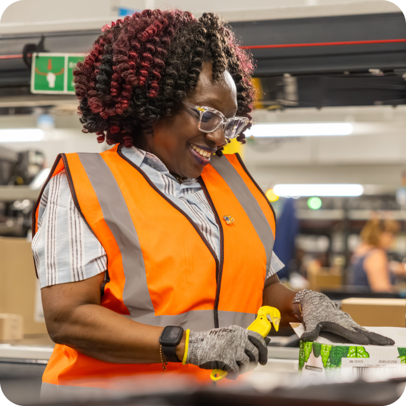 Female associate in the warehouse working and smiling while wearing a safety vest