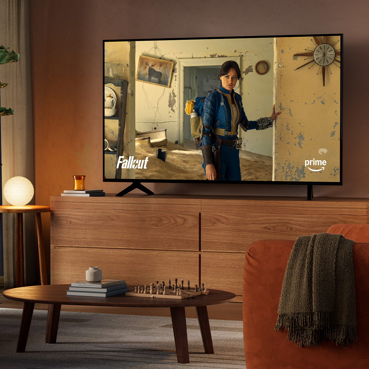 Un salon à la lumière tamisée, de nuit, avec une télévision sur une console. À l'écran : Fallout