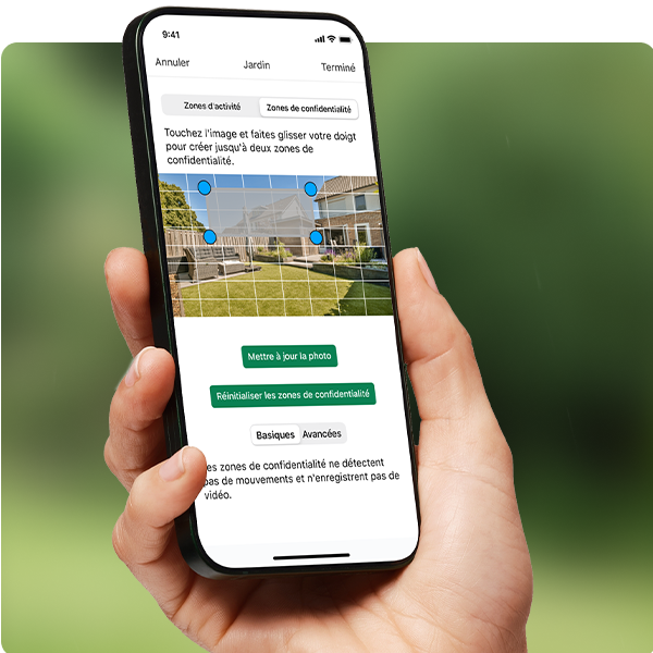 Une personne tenant en main son smartphone utilise l'application Blink pour configurer des zones de confidentialité dans le menu Paramètres.
