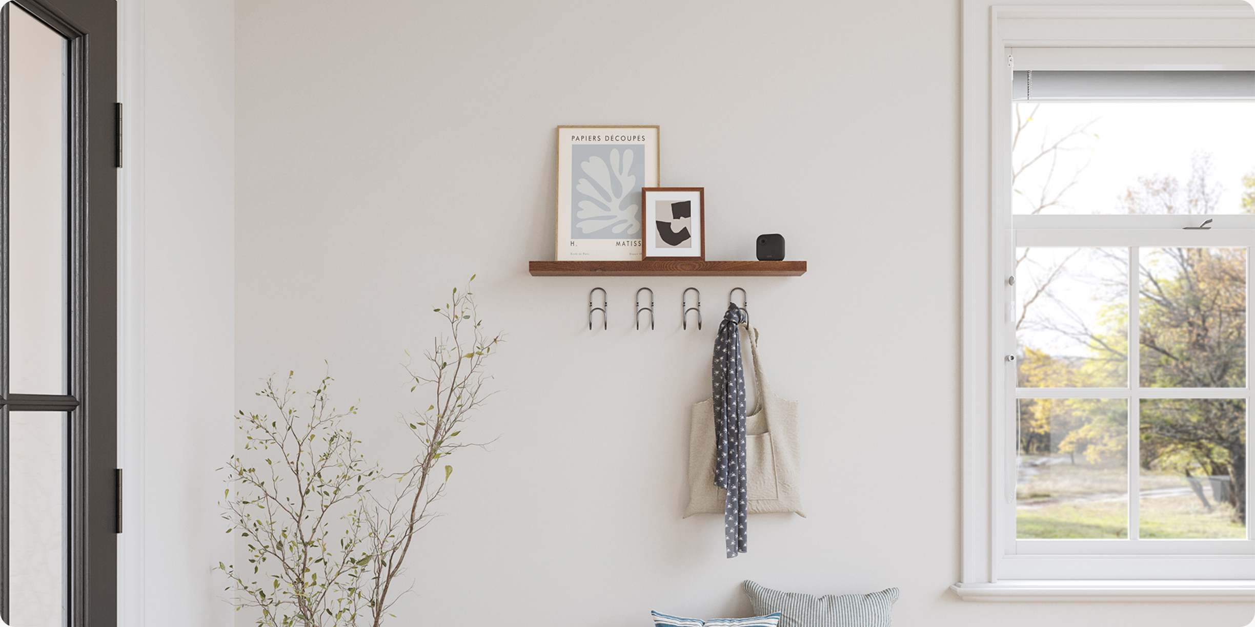 Blink Outdoor 4 est placée sur une étagère dans l'entrée d'une maison et se fond parfaitement avec le décor environnant aux tons neutres.