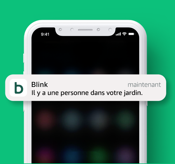 Une notification de l'application Blink est affichée sur un téléphone et indique la présence d'une personne dans le jardin.