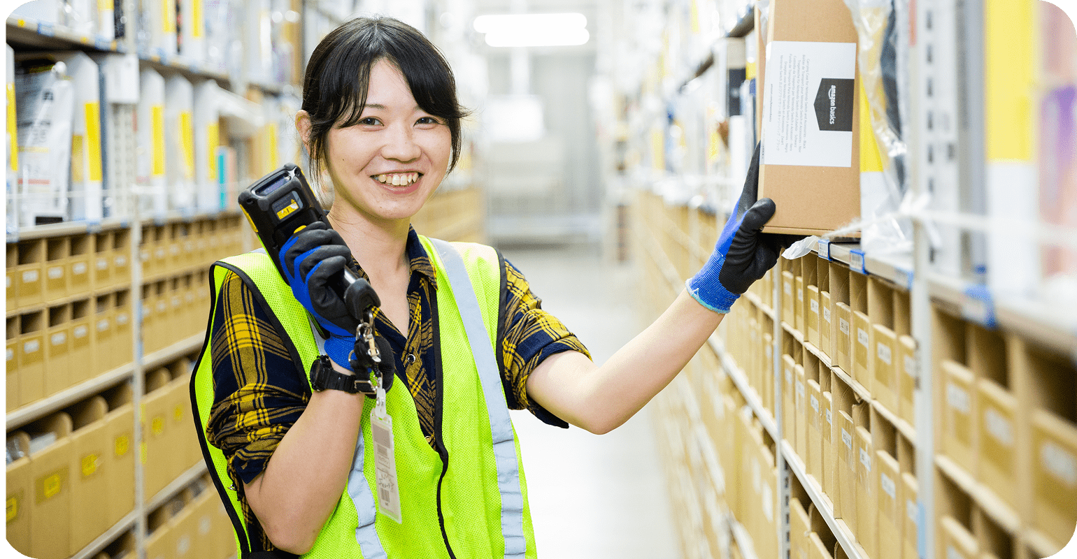 安全ベストを着た倉庫スタッフが、商品が並んだ明るい倉庫施設で荷物の仕分けをしています。