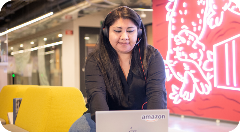 Person with headphones working on Amazon laptop at yellow chair