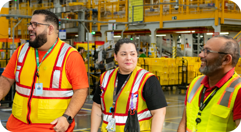Three associates in safety vests at fulfillment center.