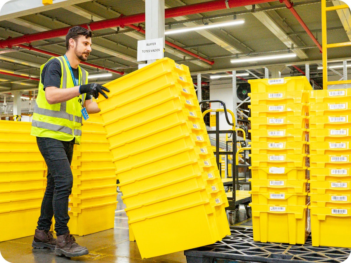 Associate in safety vest handling yellow storage containers in fulfillment center