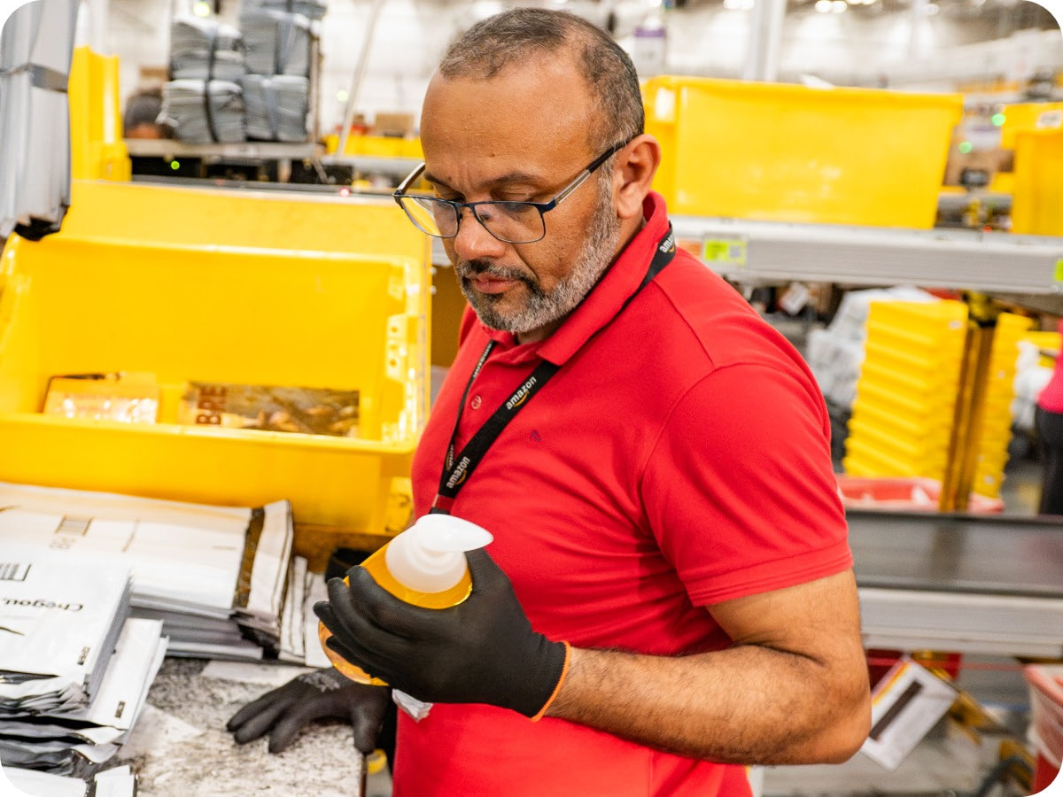 Associate in red shirt scanning package at fulfillment center workstation