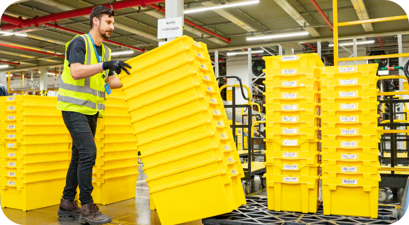 Associate in safety vest handling yellow storage containers in fulfillment center
