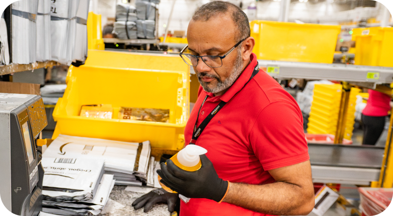 Associate in red shirt scanning package at fulfillment center workstation