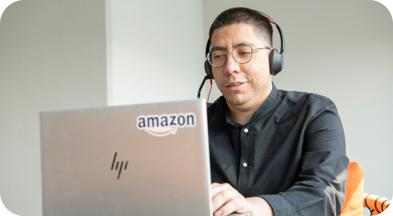 Person with headset working on laptop displaying Amazon logo