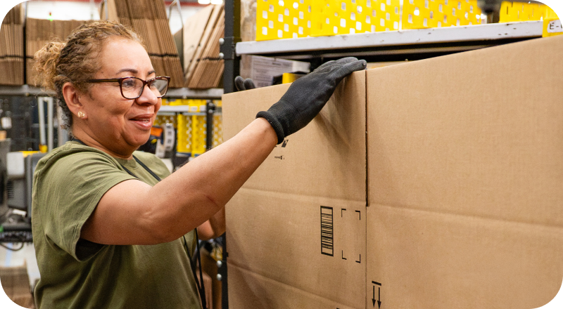 Associate in glasses and gloves handling a cardboard package in fulfillment center