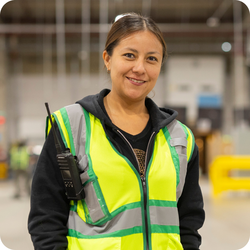Associate in safety vest with scanning device smiles in fulfillment center