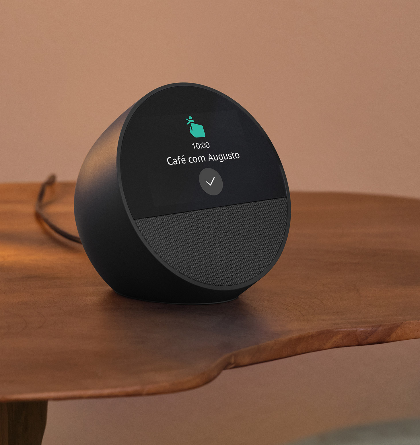 O Echo Spot está na mesa de cabeceira. A display de 2,8” mostra o lembrete “Ioga com Daniel às 10h” e o ícone de uma mão com o dedo indicador levantado e com uma fita.