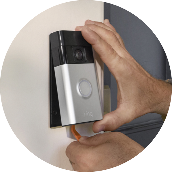Un par de manos usan una herramienta para retirar el Timbre con cámara inalámbrico Ring de un soporte de pared.