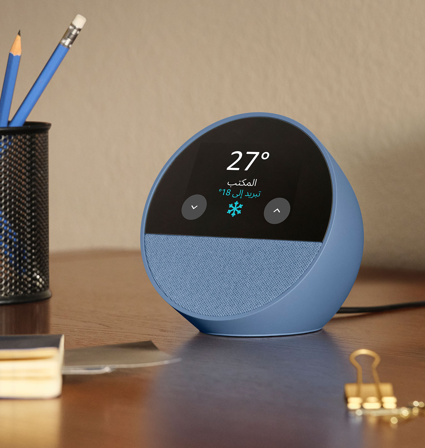 جهاز Echo Spot على مكتب. تعرض الشاشة بحجم 2.8 بوصة الطقس ودرجة حرارة الثيرموستات في المكتب المنزلي.  تُظهر أيقونة الثيرموستات النص "تبريد الحرارة إلى 22 درجة."