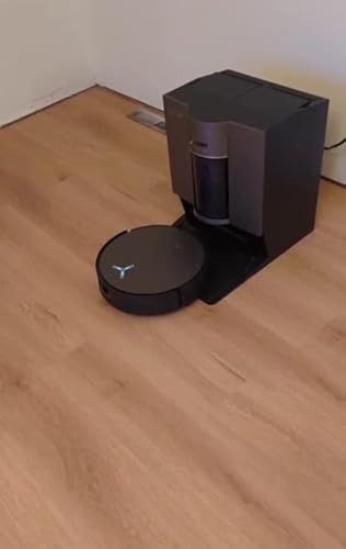 Ein schwarzer ECOVACS X11 OMNICYCLONE Saugroboter bewegt sich selbstständig über einen hellen Holzboden und dockt erfolgreich an seine braun-schwarze Ladestation an. Das Video zeigt die automatische Navigation und Andockfunktion des Roboters in Aktion. Der Roboter kehrt präzise zur Station zurück und positioniert sich korrekt zum Laden.