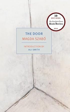 The Door, pale grey book cover depicting the corner of a room, with the title in a faded blue box in the center of the cover.