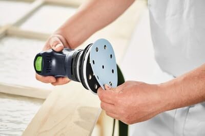 Hands attaching a sanding disc to the Festool ETS 125 REQ-Plus sander's pad.