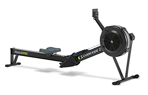 Concept2 RowErg Indoor Rowing Machine in black and silver finish on epoxy-coated garage floor, the air-flywheel visible at the front with the PM5 monitor mounted on the swing arm above, the seat positioned mid-stroke on the aluminum rail, caster wheels at the base showing the unit can roll for storage, the chain-and-handle visible between the seat and the flywheel housing -- the canonical Garage Gym Reviews, Wirecutter, and BarBend top pick for indoor rowing year after year and the only piece of home gym gear with a documented 30-year service life.