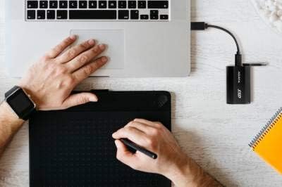 ADATA SE800 SSD connected to a laptop, demonstrating its use for creative work.