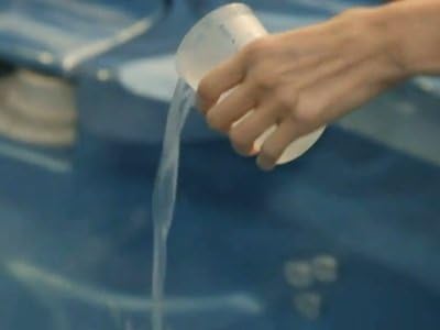 Hand pouring AquaFinesse solution into a hot tub