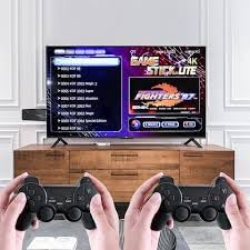 A television screen displaying the game selection menu of the Gamestick Lite, with two hands holding wireless controllers in the foreground.