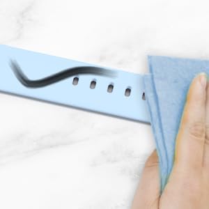 A hand wiping a light blue fitness tracker band with a cloth, demonstrating easy cleaning of dirt.