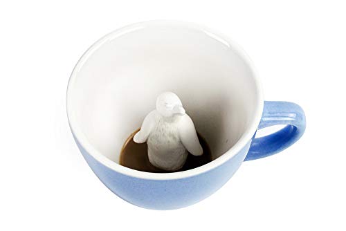 Ice blue ceramic coffee mug with a small three-dimensional penguin figure inside, visible once the coffee is poured