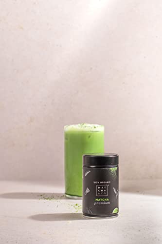 Frasco de té matcha premium junto a un vaso de matcha preparado con leche, presentando una bebida suave y energética
