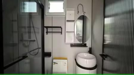 Interior view of a bathroom within the prefab house, featuring a sink, toilet, and shower area.