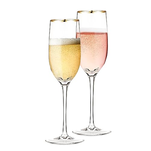 two crystal champagne flutes with thin gold rims standing on a table