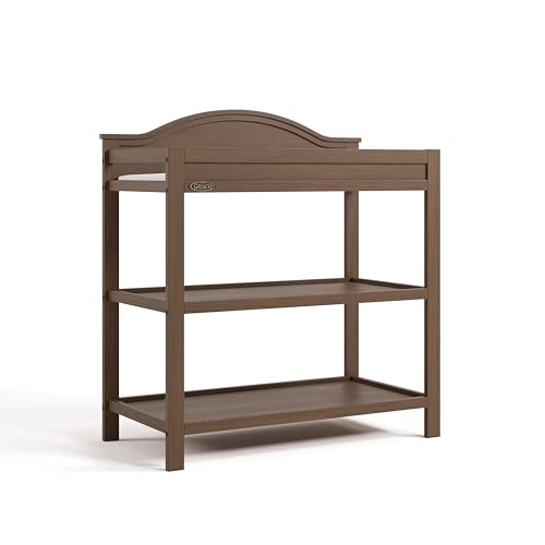 Image of Graco Story Changing Table with Water-Resistant Pad - GREENGUARD Gold Certified Baby Changing Station with Safety Strap, 2 Open Shelves, and a Nursery Must-Have Design (Hazelnut)