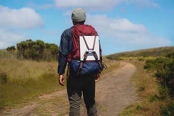 Person walking with a backpack, with the Starlink Mini antenna attached to the back