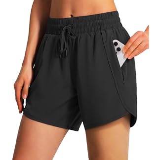 Woman placing a phone into the zippered side pocket of black Ksmien women’s running shorts with pockets.