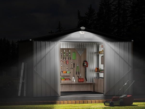 Shed interior illuminated by a solar light at night, showing organized tools.