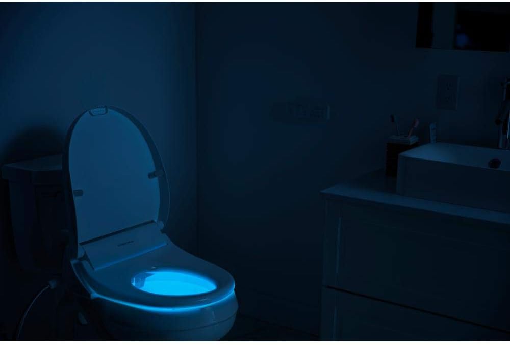A toilet with a soft blue night light illuminating the bowl in a dark bathroom setting.