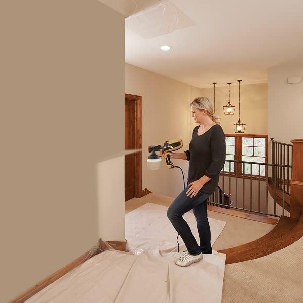 A woman spraying an interior wall with the Wagner FLEXiO 590 paint sprayer, demonstrating indoor application.