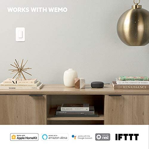 A WeMo light switch installed on a wall, with logos for Apple HomeKit, Amazon Alexa, Google Assistant, Nest, and IFTTT below, indicating compatibility.