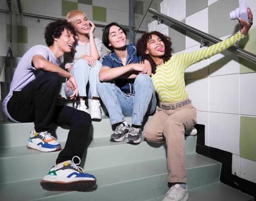 Cuatro amigos en una escalera tomando un selfie con una cámara Instax Mini 12 mientras se divierten.